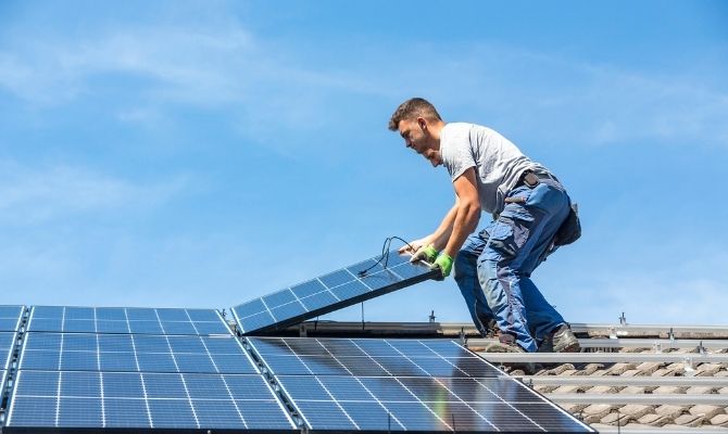 two men installing solar panels on the roof